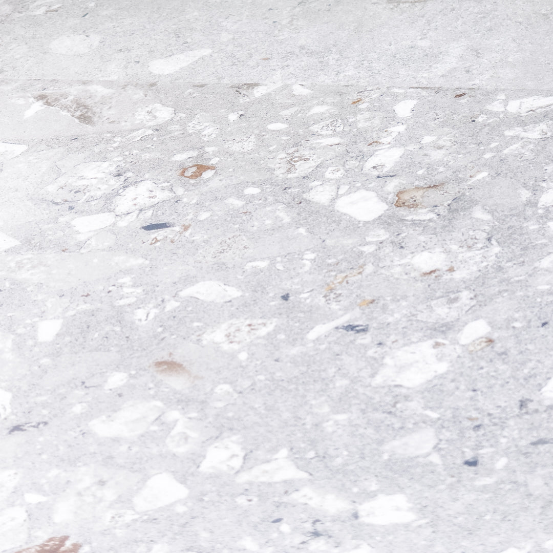 Angled close up of two 36x36 cement terrazzo look tiles called oasis pearl they have a light grey stone base with light and grey flecks. 