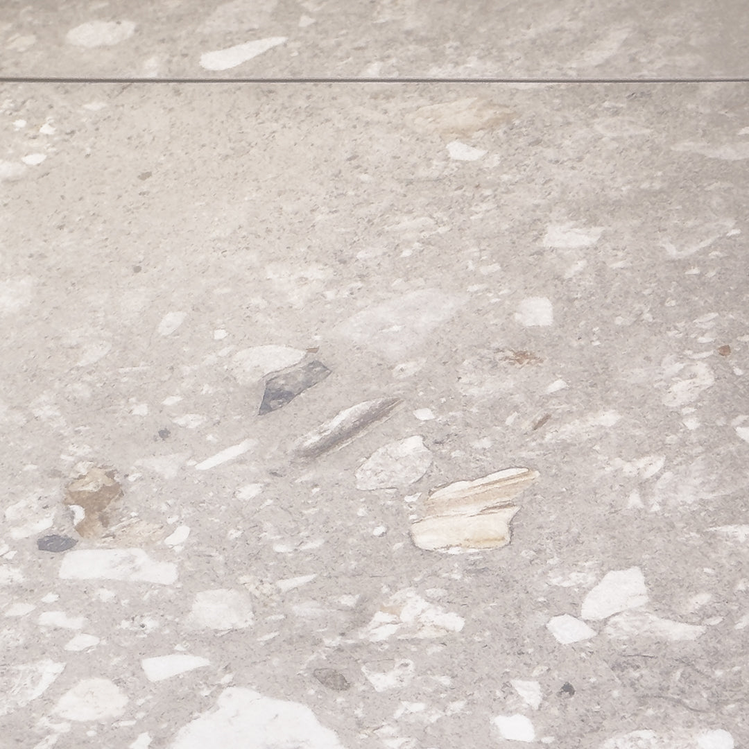 a close up of two 36x36 porcelain terrazzo cement look tiles in a warm grey beige base with light and dark flecks.