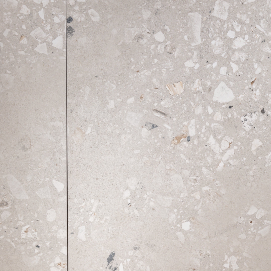 a side by side of two 36x36 porcelain terrazzo cement look tiles in a griege base with light and dark flecks.