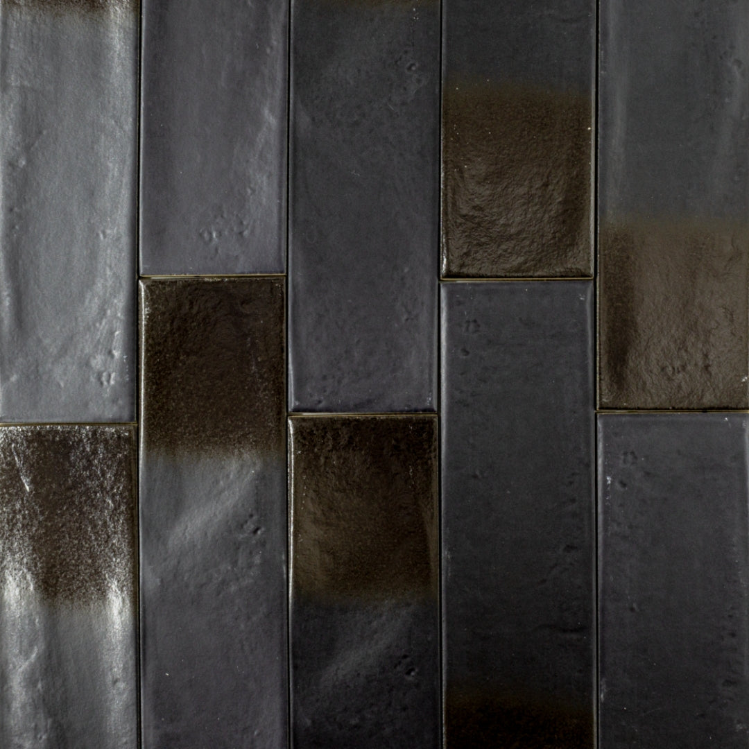 Ariel view of 3x12 glossy textured black tiles in a brick layout showing the finish and colour variance. 