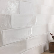 A close up of a tile install where the tiles are light grey 3x12 glossy variated colour tile. 