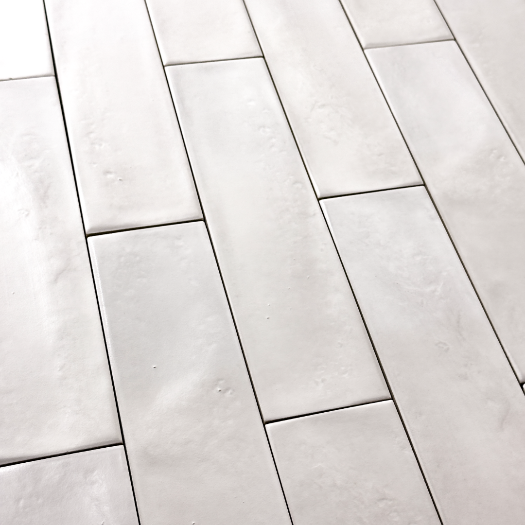 Angled close up of 3x12 glossy textured white tiles in a brick layout showing the finish and colour variance. 