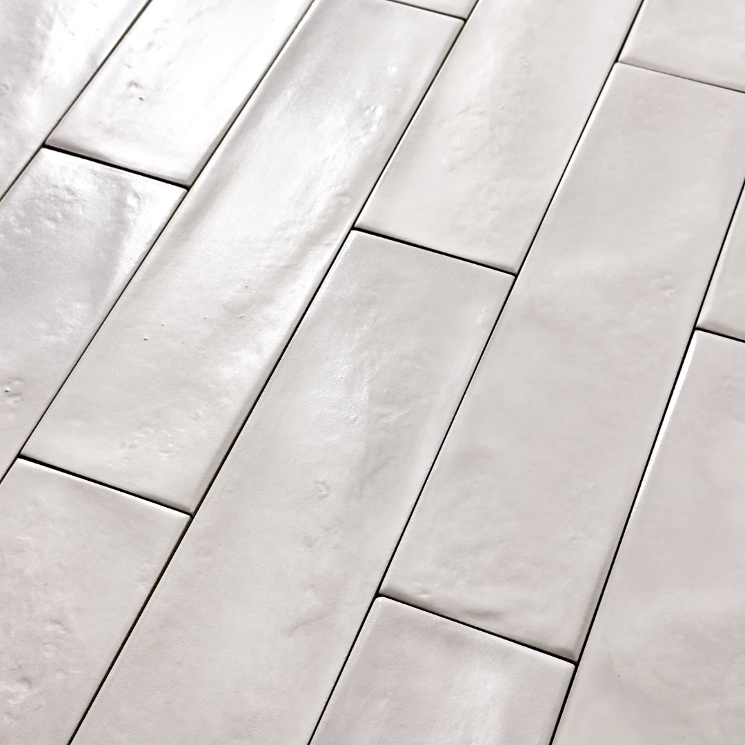 Angled close up of 3x12 glossy textured white tiles in a brick layout. 