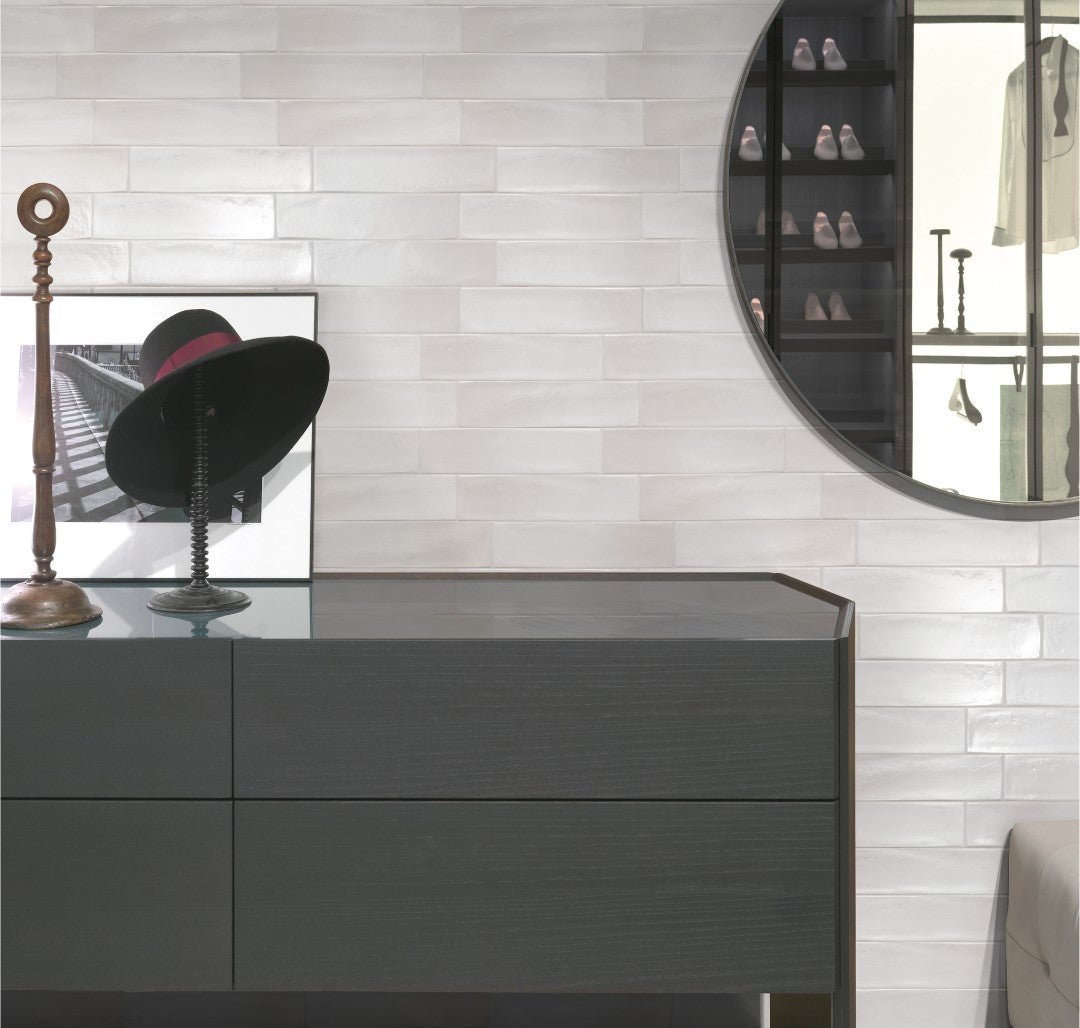 A closet tile installation with 3x12 glossy white tiles with texture and colour variance. The closet fixtures and furniture are black. 