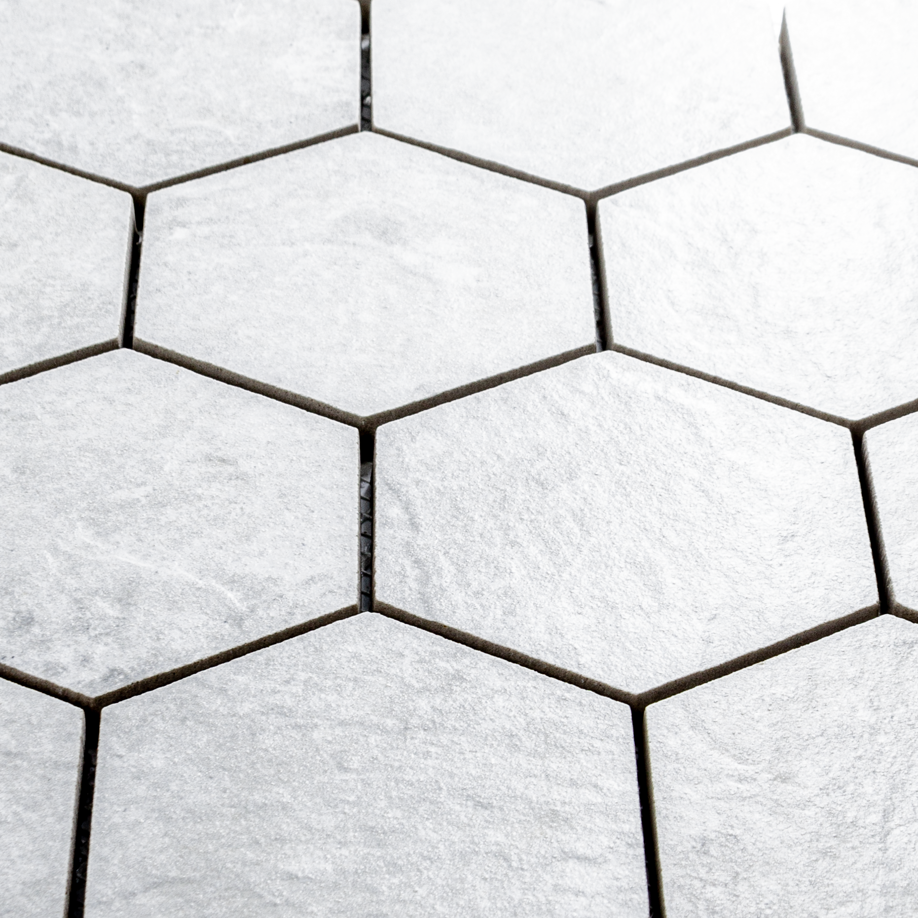 Angled close up of A 3" hexagon mosaic tile in a light white stone look. 