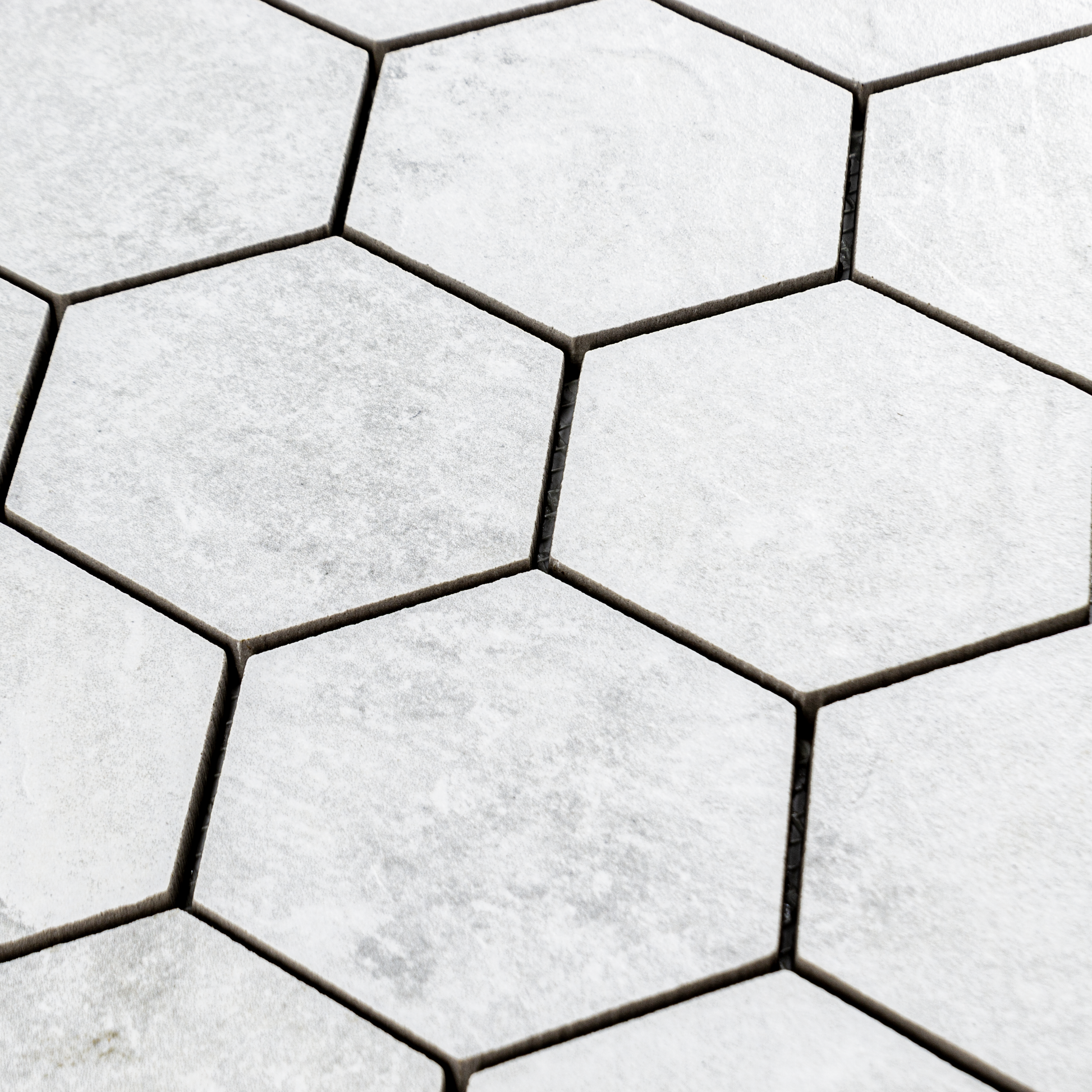 Angled ariel view of A 3" hexagon mosaic tile in a light white stone look. 