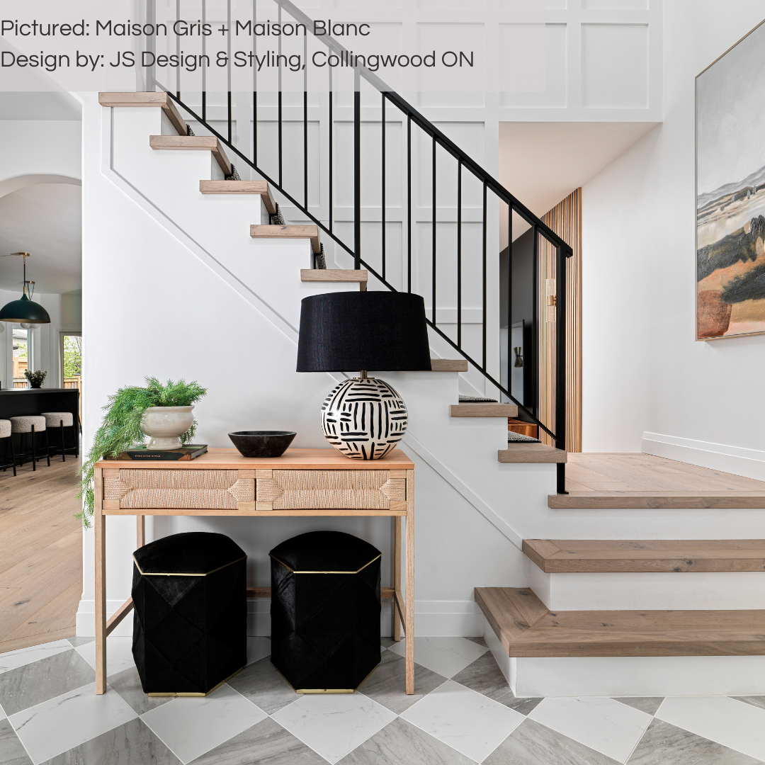 A sophisticated light wood and white foyer with the view of the stairs landing. The entrance has maison luxury marble look grey and white tiles in a diamond checker layout. 