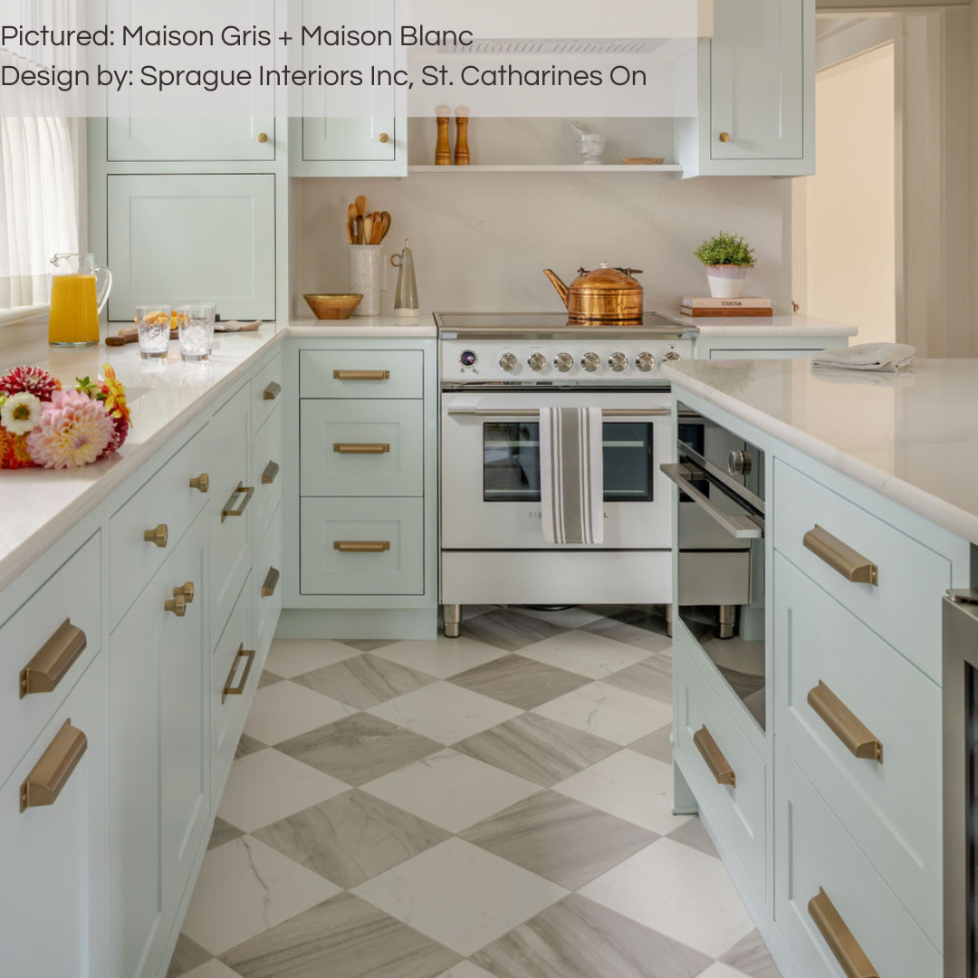 A classic transitional kitchen with pale seafoam blue cabinets, gold hardware and our grey and white maison marble look checker tiles installed on the floor. 
