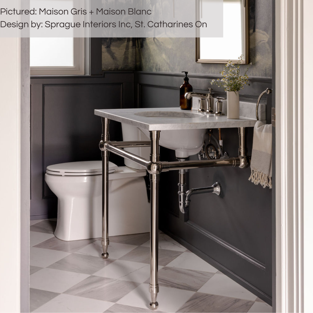 A stunning regal powder room with black wainscotting, patterned wallpaper and exposed pipe sink. The floor tiles are a soft spin on a traditional checkerboard pattern with white and grey marble look tiles. 