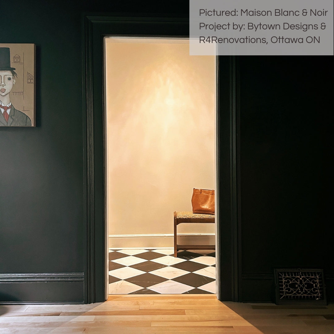 From the perspective of a den or study, we are looking towards a hallway with black and white maison marble look checker tiles installed on the flooring. 
