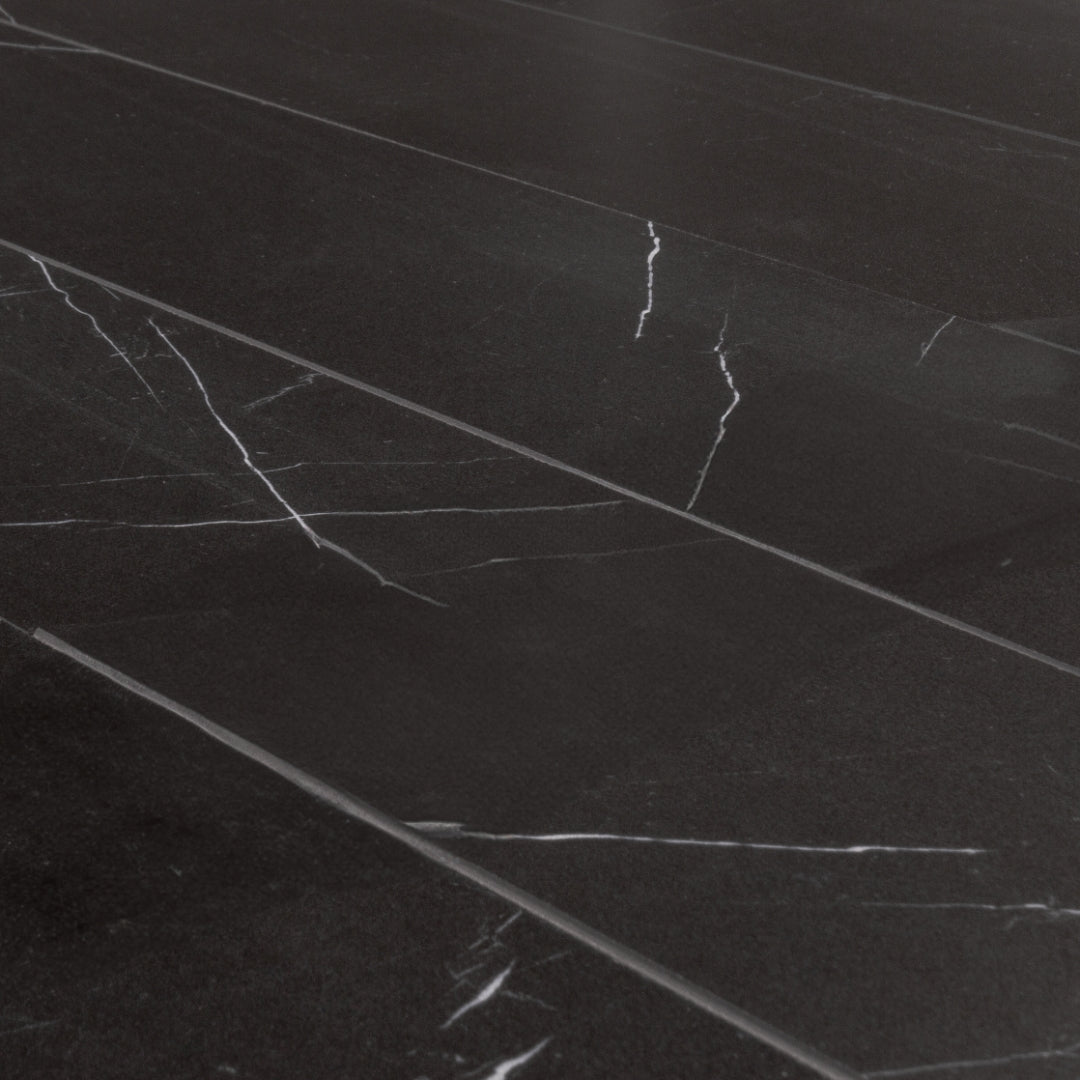 Angled close up view of a five 4 x 20 chevron tiles in matte black marble look porcelain with white veining. 