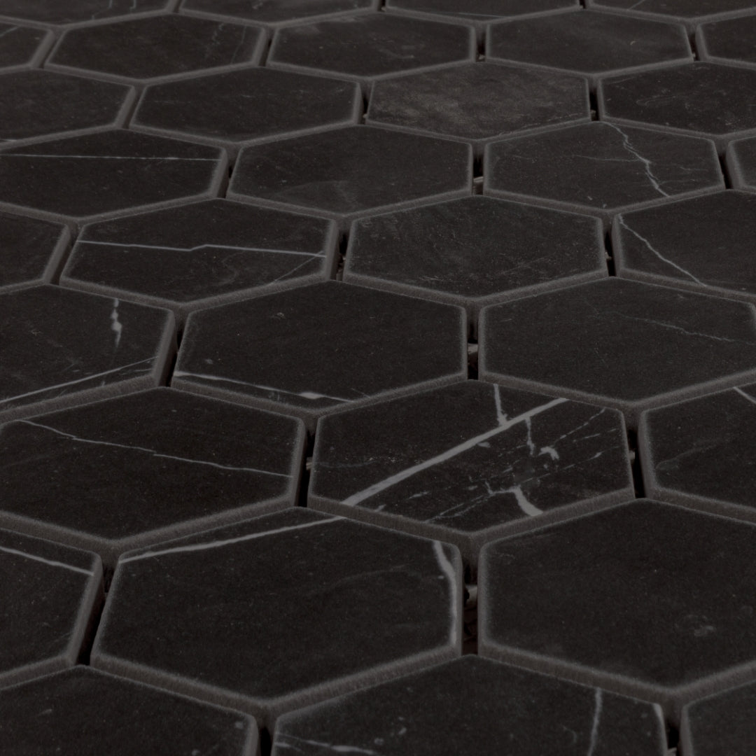 Angled close up view of a matte black marble look porcelain hexagon mosaic tile sheet. 