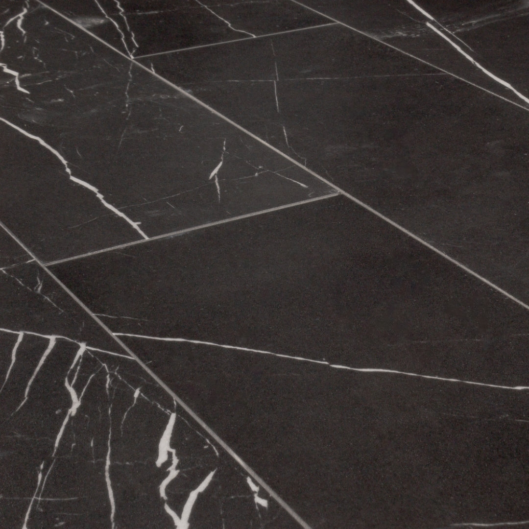 Angled close up view of 4x12 tiles in polished glossy black marble look porcelain with white veining. They are laid out in a brick pattern. 