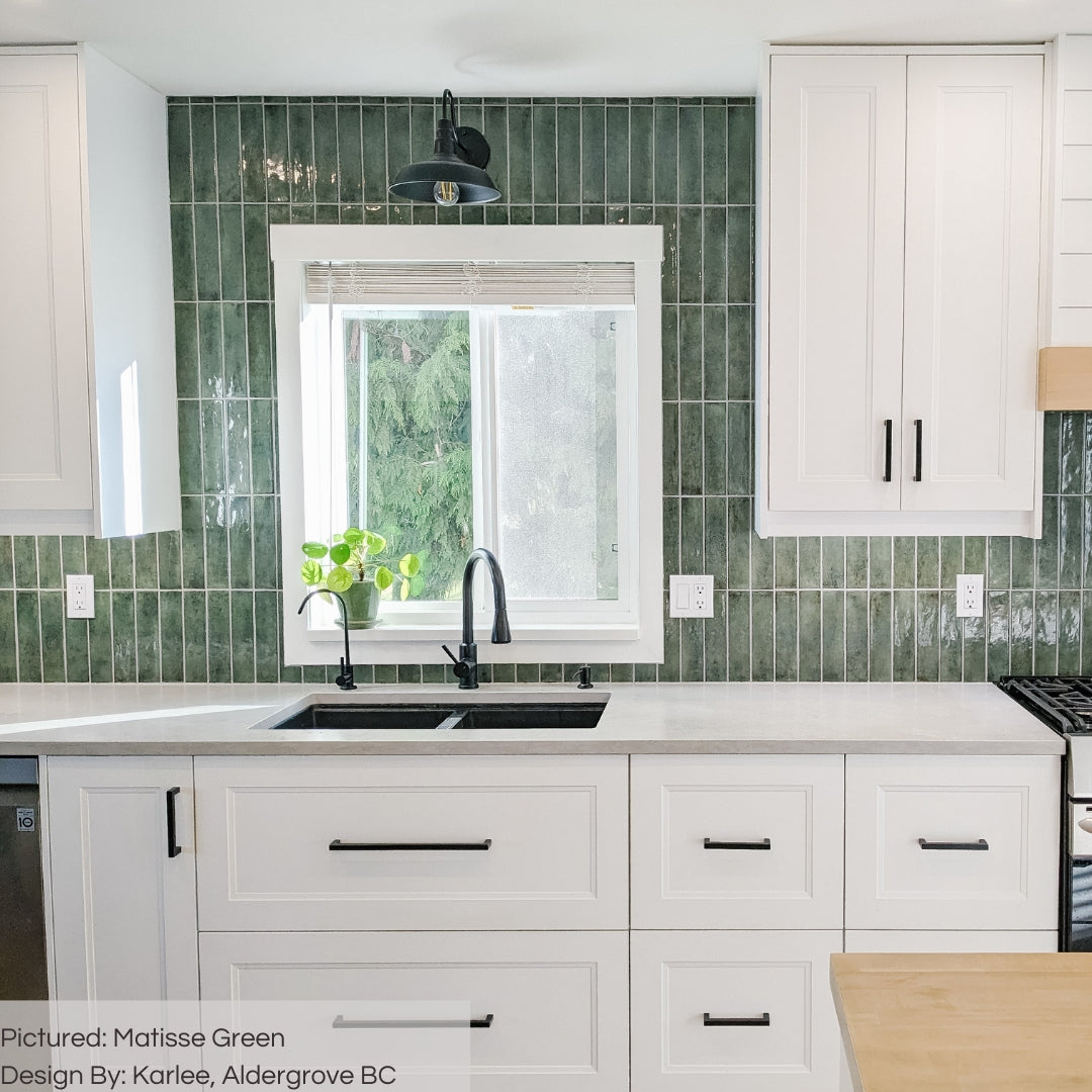 A bright white kitchen with matisse green glossy subway tiles installed in a vertical stack 