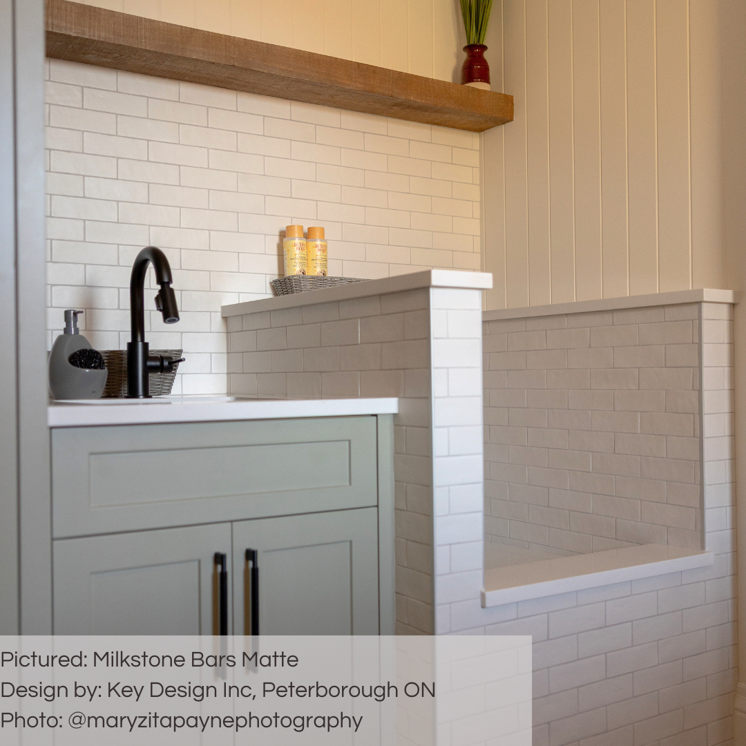 A tiled mudroom backsplash wall and doggy shower tiled featuring 2x6.5 milkstone bars; a matte off white cream tile with heavy colour variation. 