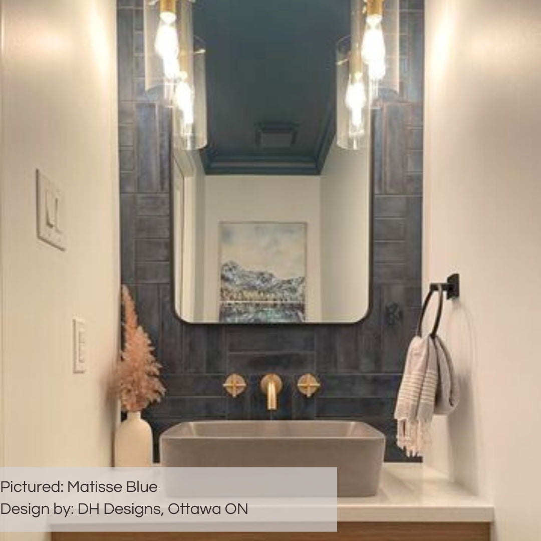 A luxurious navy and white powder room with matisse blue glossy tiles on the backsplash running up the length of the wall.