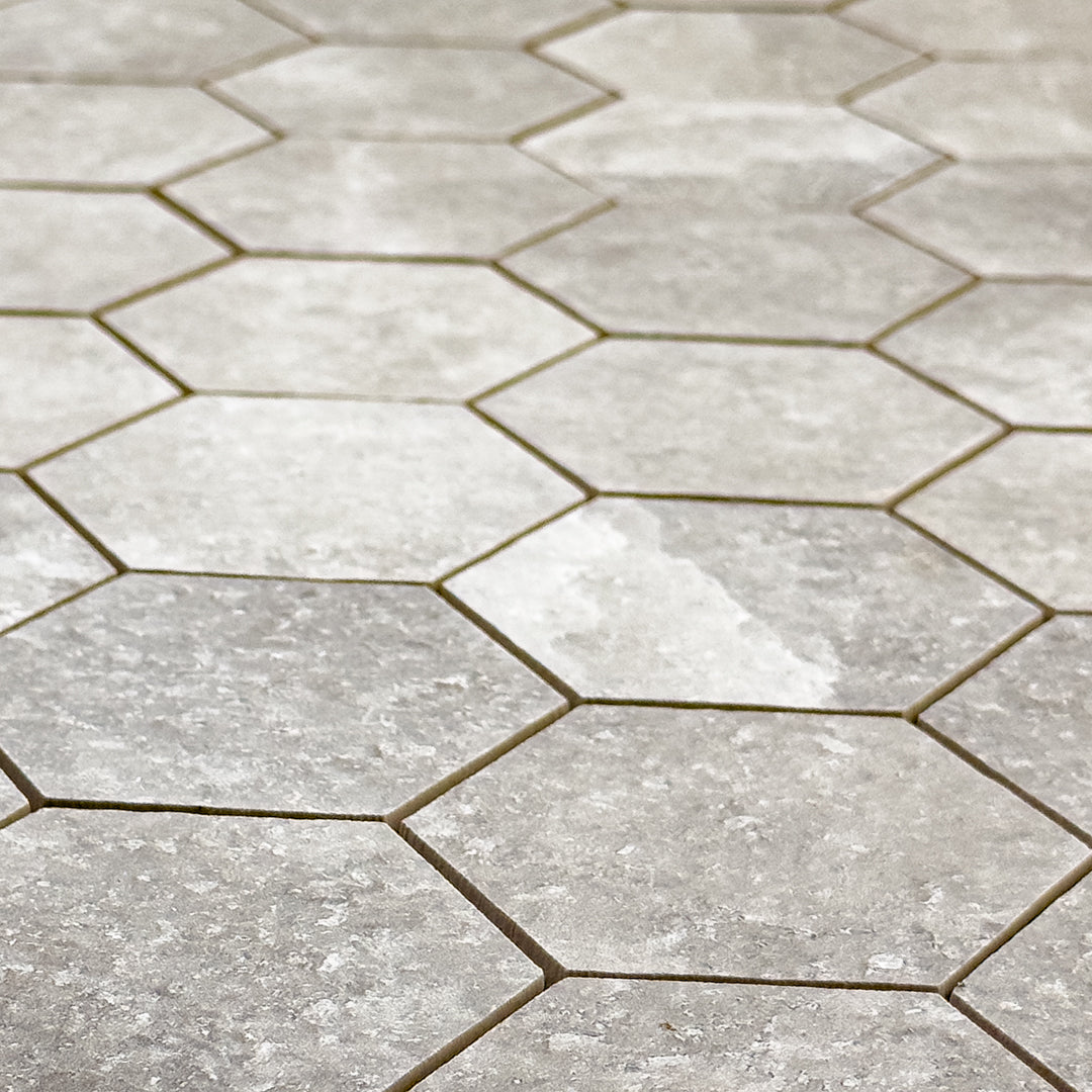 Angled ariel view of A 3" hexagon mosaic tile in a beige taupe stone look showing the colour variation and texture. 