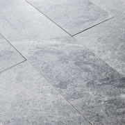 Angled close up of a group of 4x24 light grey stone look tiles in a brick layout. 