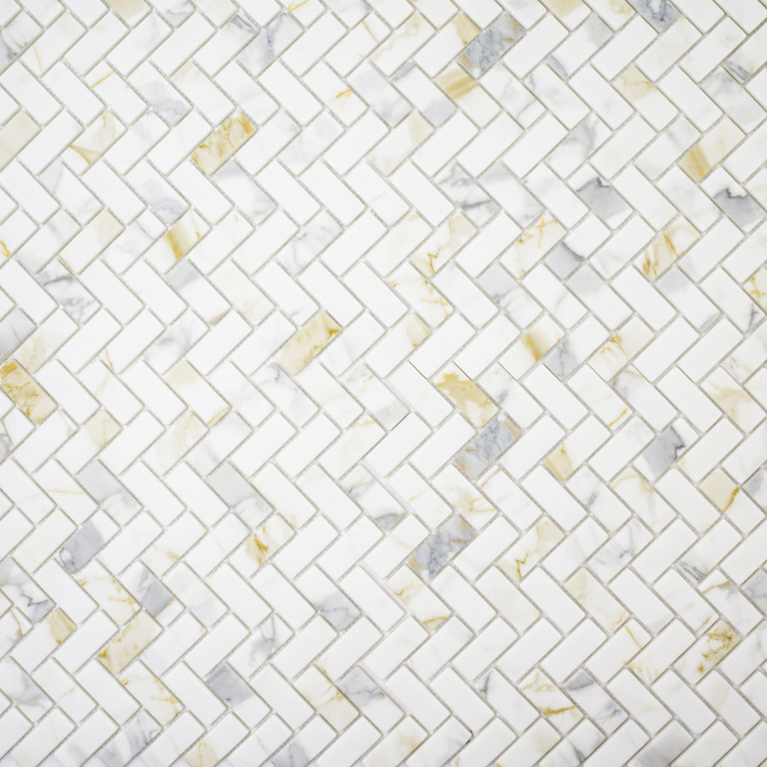 Ariel view of herringbone mosaic tiles the tiles are white and have a gold and grey marble veining pattern. 