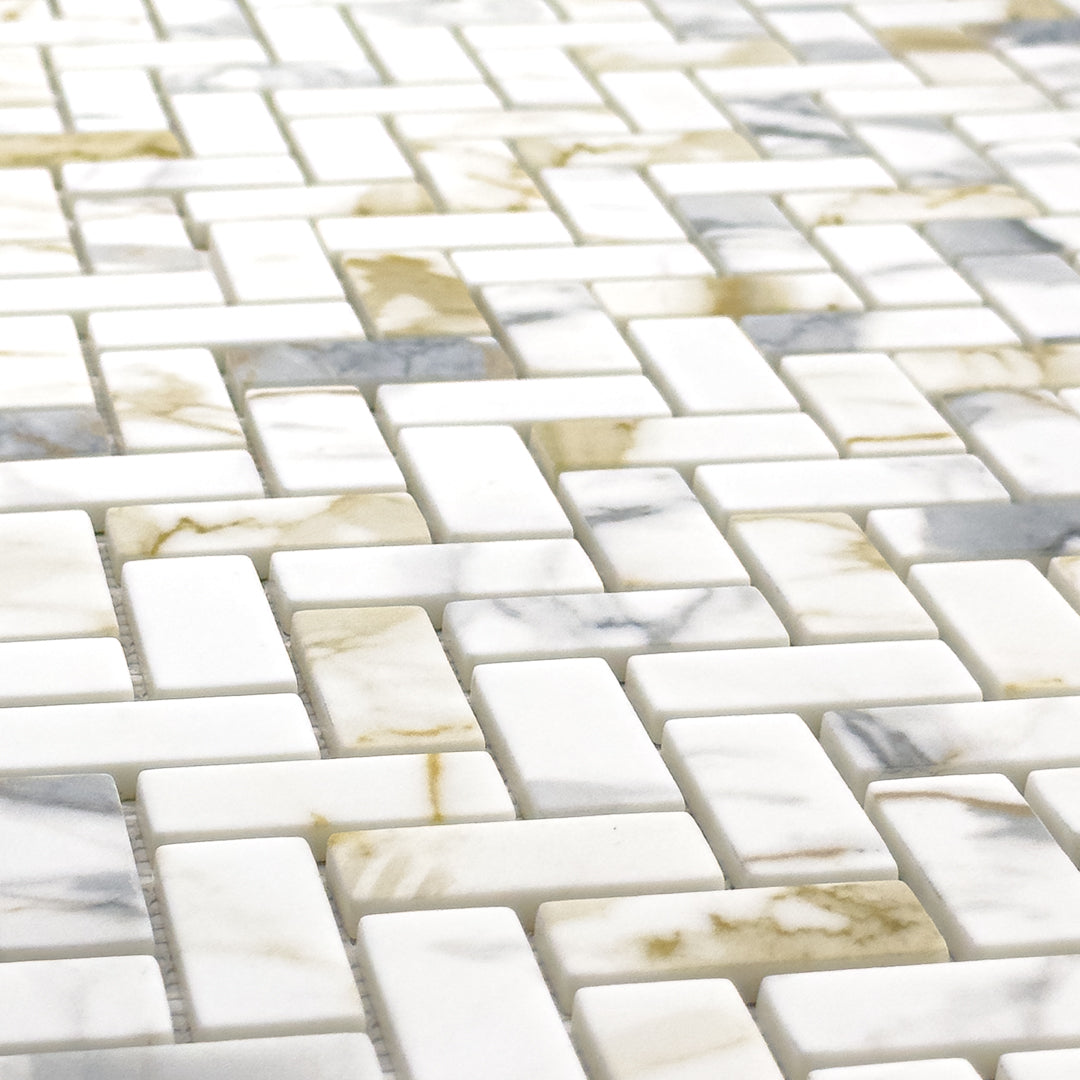 Close up angled view of herringbone mosaic tiles the tiles are white and have a gold and grey marble veining pattern. 
