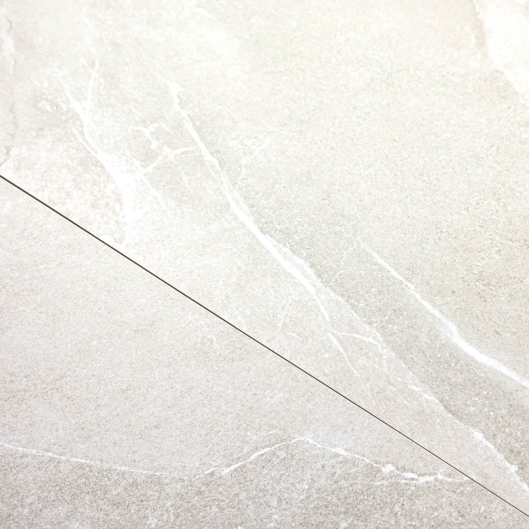 Close up of two tiles edge to edge to highlight the colour and veining of the 24x24 square limestone look light grey tile stonehaven