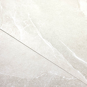 Close up of two tiles edge to edge to highlight the colour and veining of the 24x24 square limestone look light grey tile stonehaven