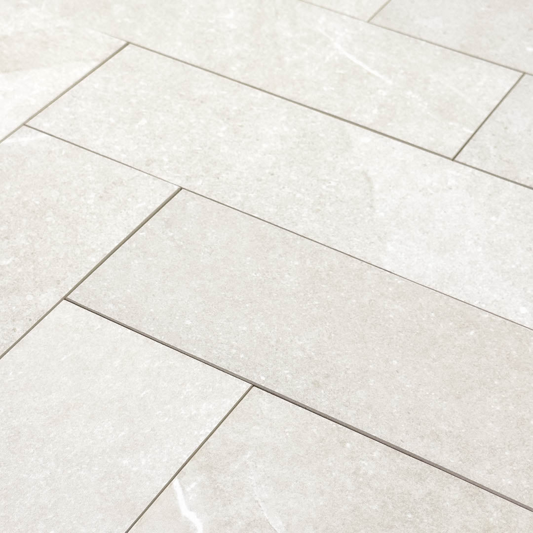 limestone look 4x12 matte tile in a light grey laid out in a brick pattern to show the pattern and variance.