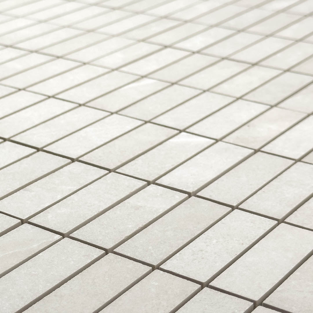 Angled close up view of a sheet of mosaic stonehaven light stone look tiles, the pieces are 1x3 stacked for a modern brick look. 