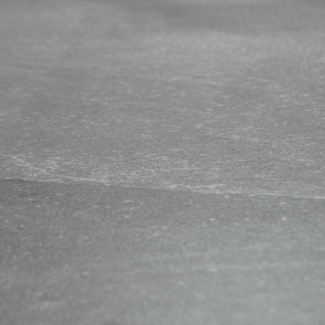 Angled close up of a 24x48 dark grey stone look tile with light thin delicate limestone look veining. The finish is matte. 
