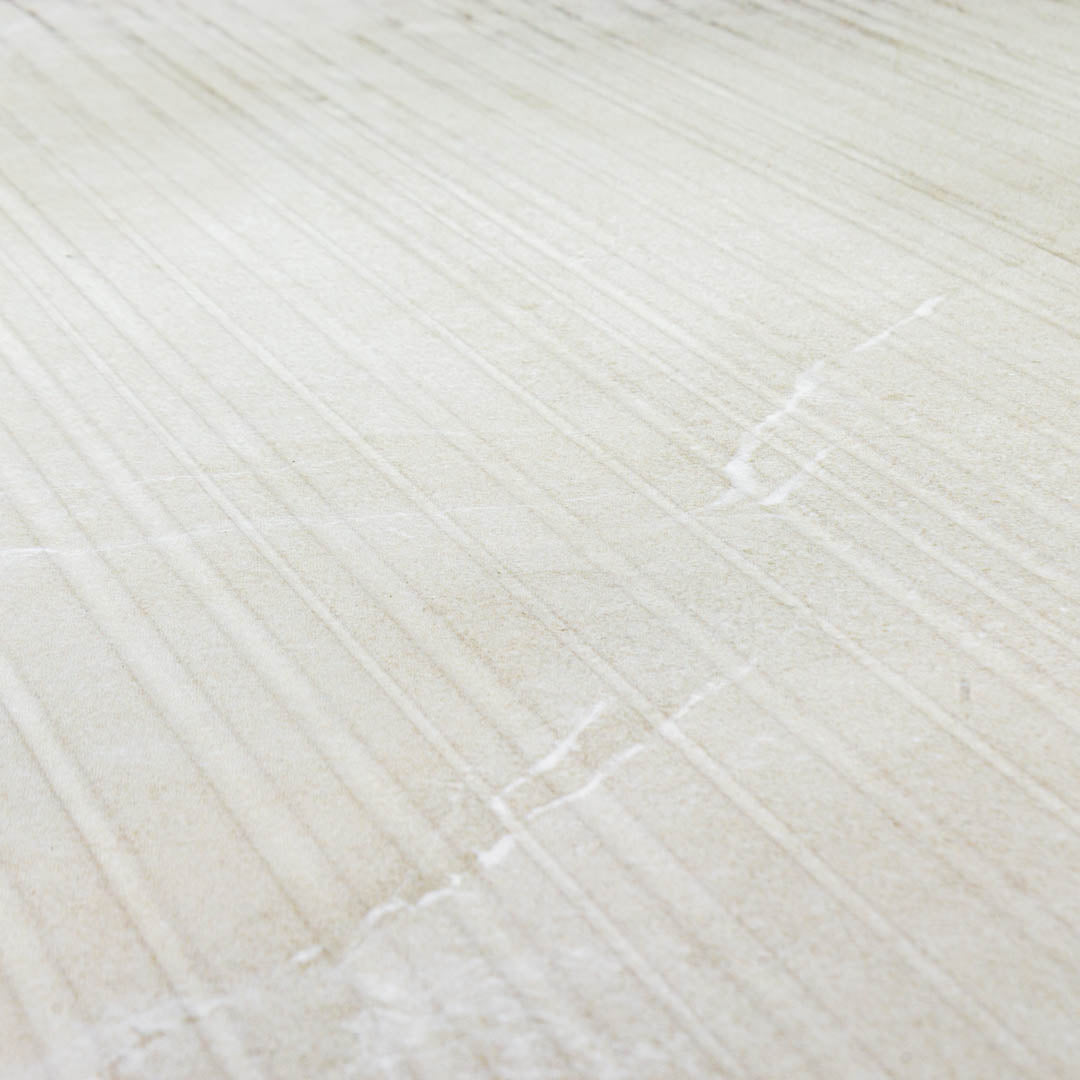 Angled close up of the ivory white limestone textured tiles that have the grain like stripes across the width of the 24x48 tile. 
