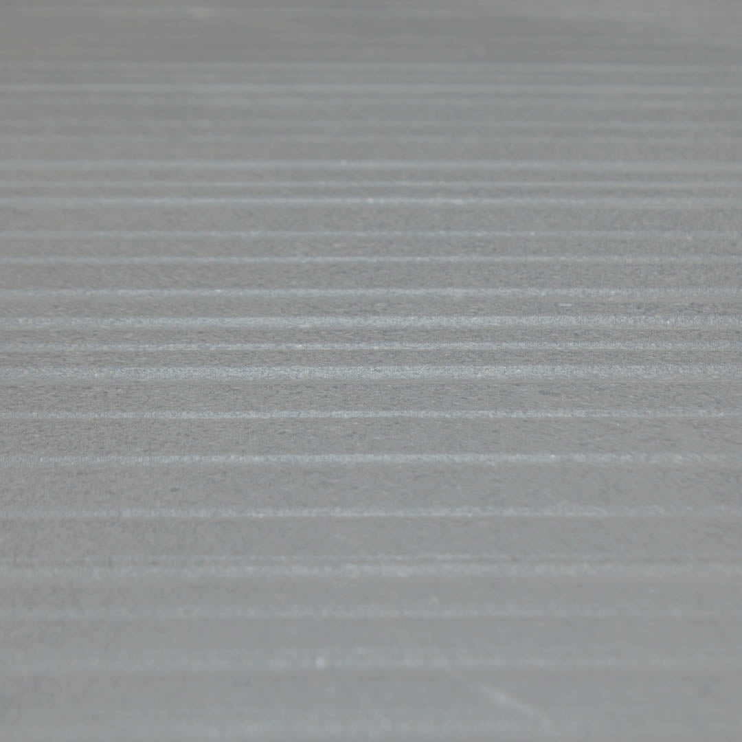 Angled close up of the dark gray limestone textured tiles that have the grain like stripes across the width of the 24x48 tile. 