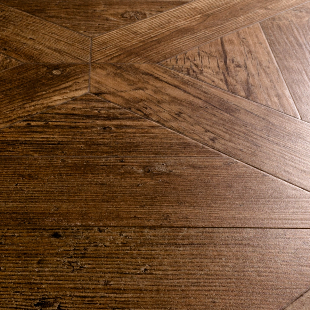 Angled close up of two 19x19 parquet wood look porcelain tiles in a medium walnut caramel brown.  
