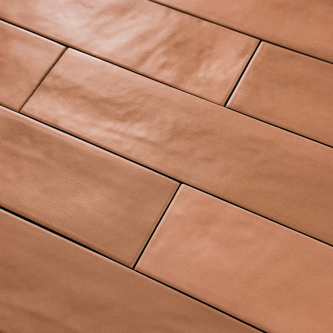 Close up detailed view of a brick layout terracotta coloured 2x9 matte subway tile to highlight the texture and colour variation in the tile. 