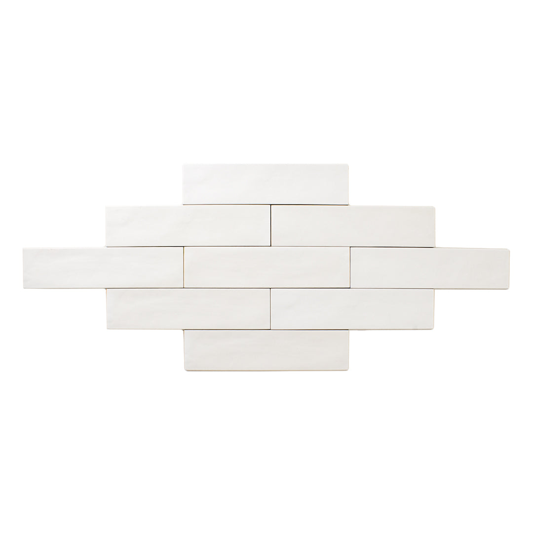 Product photo of multiple tiles laid out in a brick pattern of a 2x9 white matte subway tile with texture and colour variation. 
