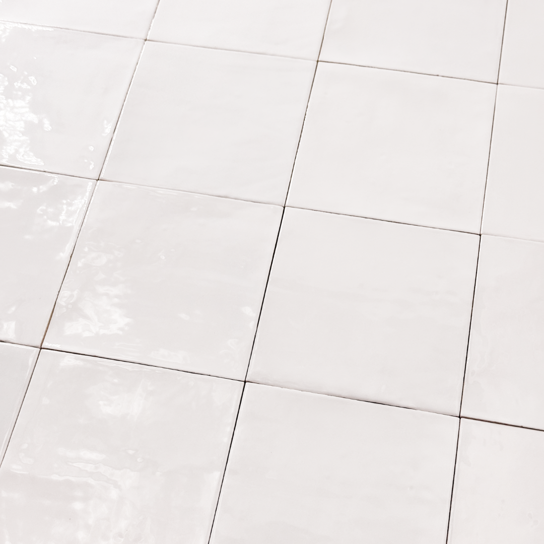 Angled ariel view of a group of glossy 5x5 textured white / offwhite zellige tiles showing the textured edges and colour variation. 