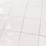 Angled ariel view of a group of glossy 5x5 textured white / offwhite zellige tiles showing the textured edges and colour variation. 