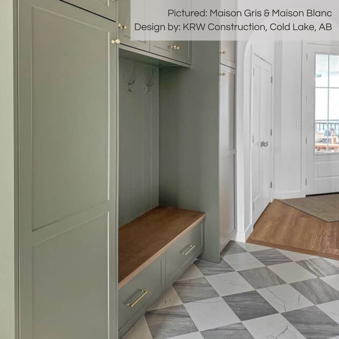 Off the bright and light front entry there is a mudroom area with an olive green and medium wood built in cabinet and seat. the floor is tiled in a diamond pattern checkerboard lay out, they are grey and white marble look maison tiles. 
