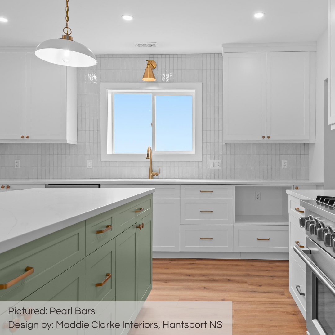 A bright and cheery kitchen with light sage green island, white cabinets and gold hardware. The Pearl Bars glossy colour variated tiles add visual texture and a timeless look! 