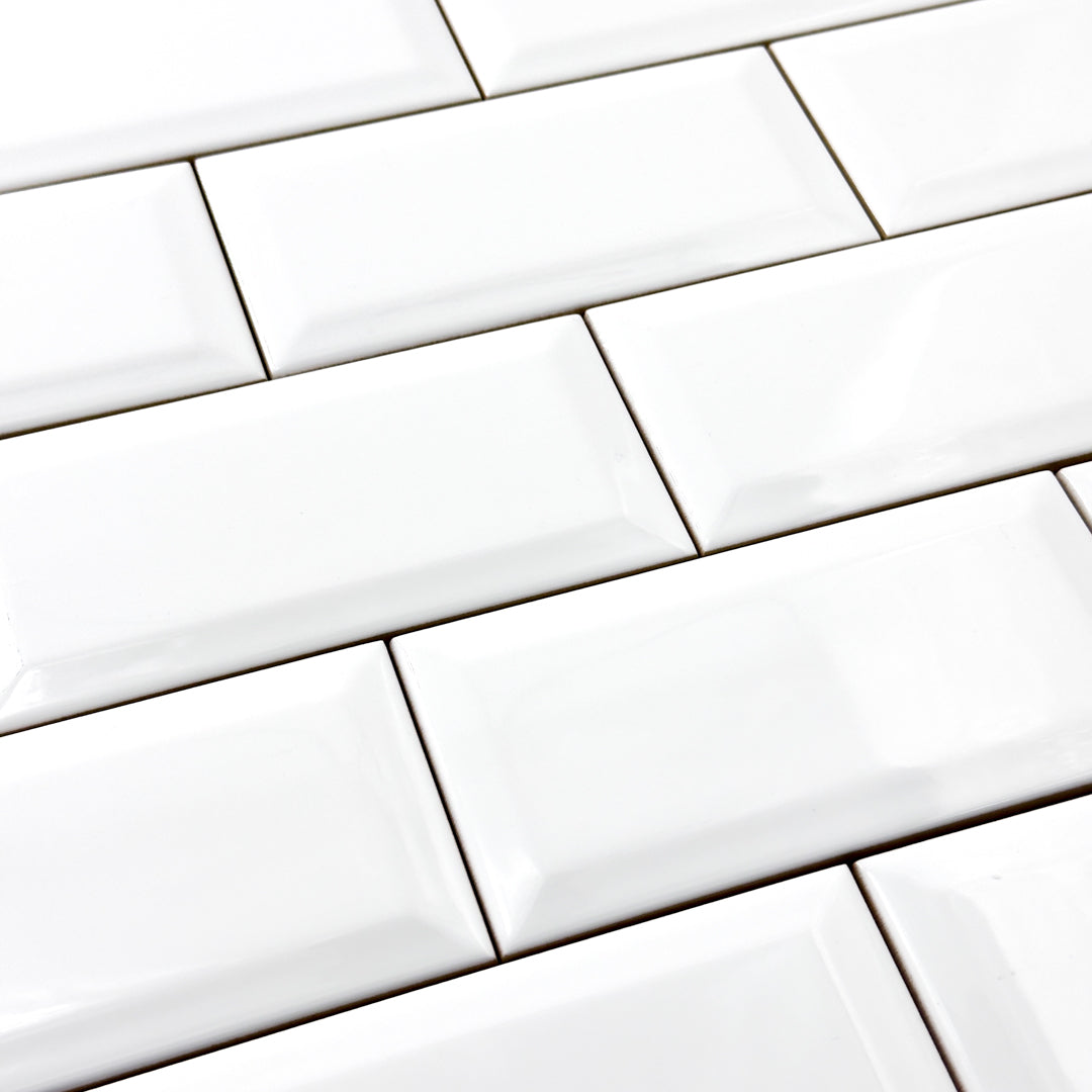 A close up of 3x6 glossy beveled white tiles in a standard brick layout. 