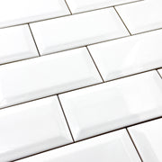 A close up of 3x6 glossy beveled white tiles in a standard brick layout. 