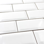 An angled close up of 3x6 glossy beveled white tile in a traditional brick layout. 
