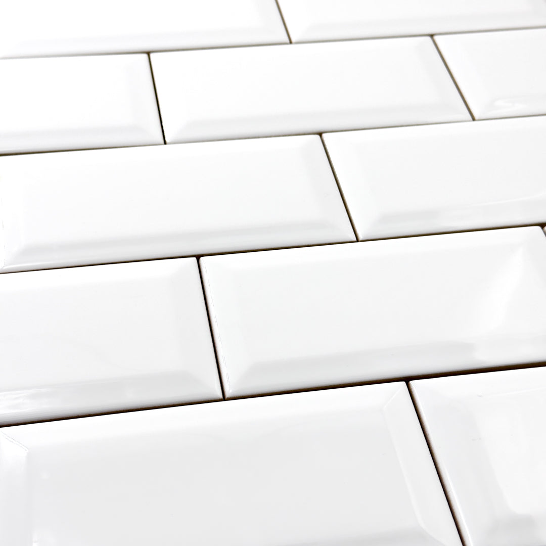 An angled close up of 3x6 glossy beveled white tile in a traditional brick layout. 