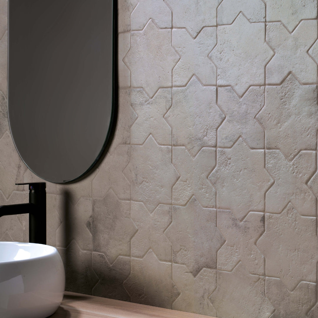 A bathroom backsplash tile installation of grey stone look star and cross tiles. 