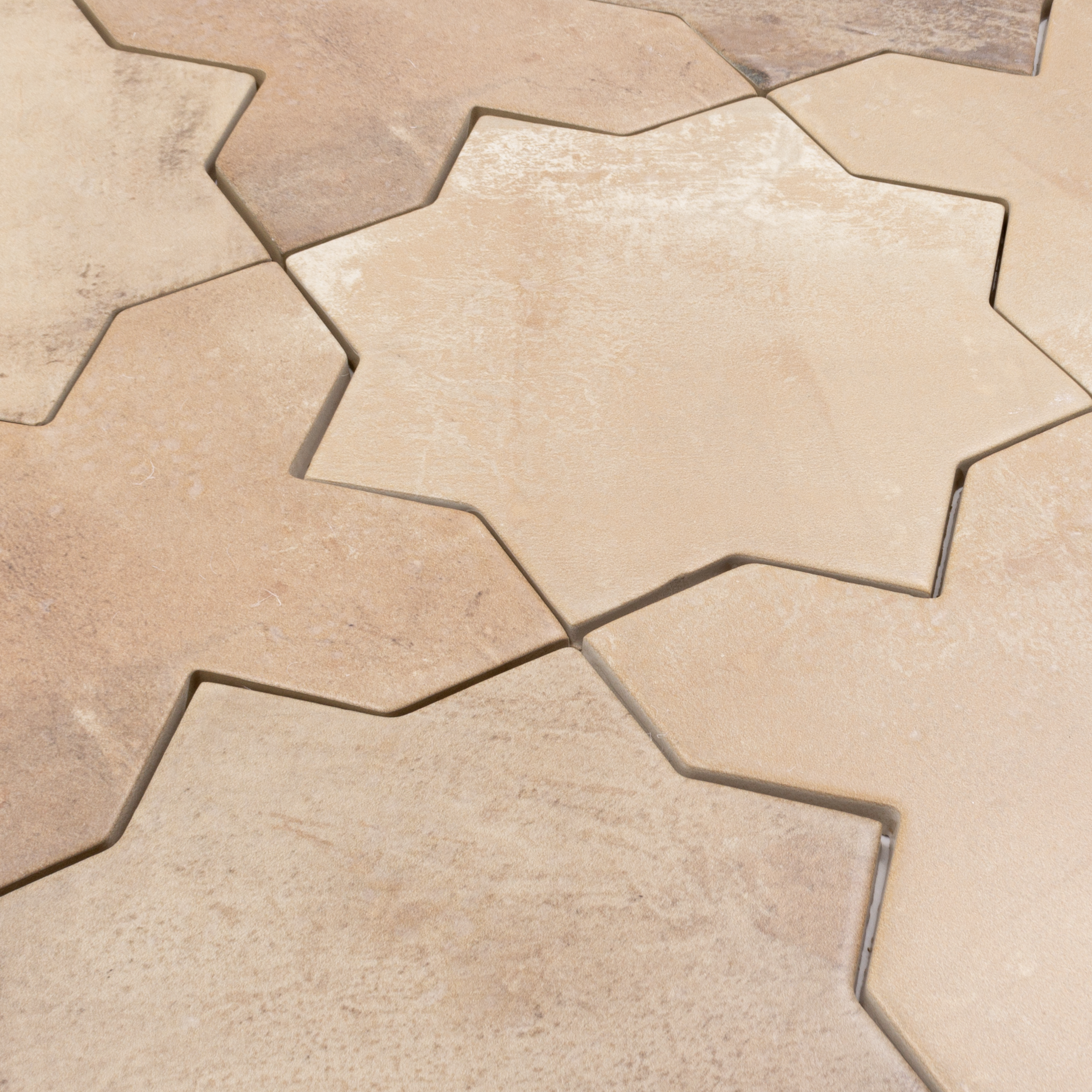 Angled close up of a group of star and cross shaped tiles interlocking together in a matte terracotta finish
