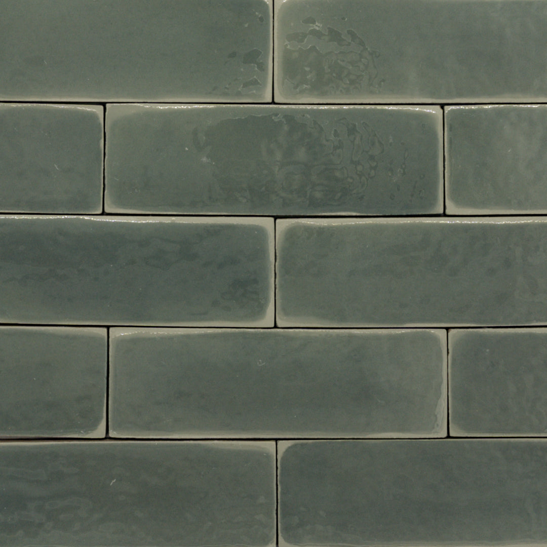 ariel view of a group of dark moss fir green 2x6 glossy subway tiles with a soft texture and uneven edges in a brick layout. 
