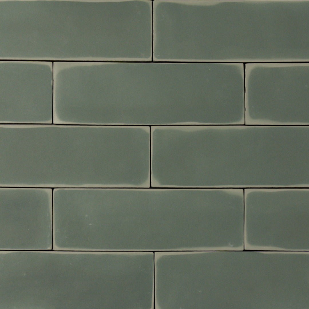 ariel view of a group of  dark moss fir green 2x6 matte subway tiles with a soft texture and uneven edges in a brick layout. 