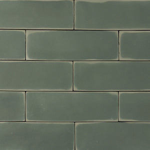 ariel view of a group of  dark moss fir green 2x6 matte subway tiles with a soft texture and uneven edges in a brick layout. 