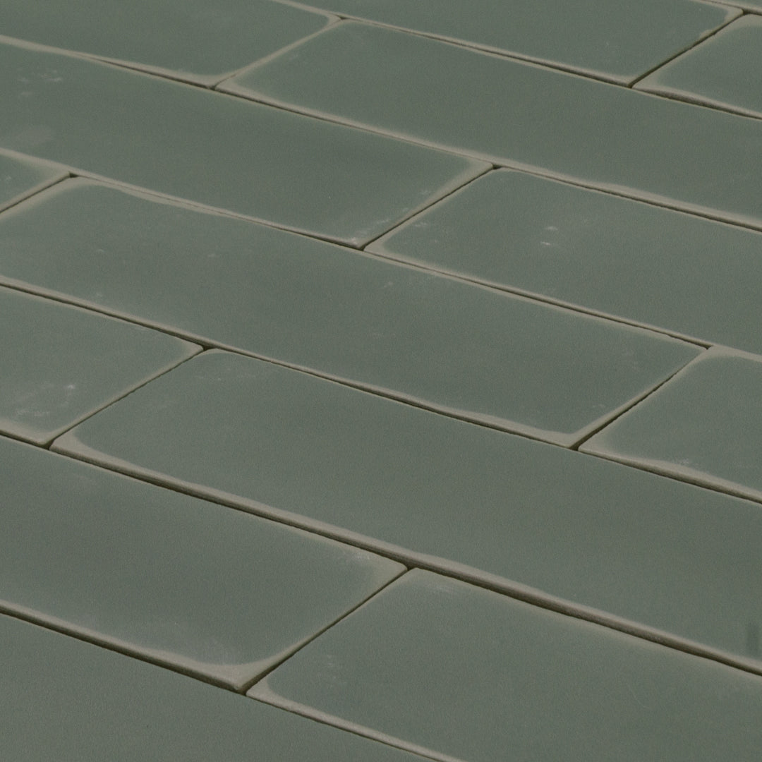 ariel view of a group of  dark moss fir green 2x6 matte subway tiles with a soft texture and uneven edges in a brick layout. 