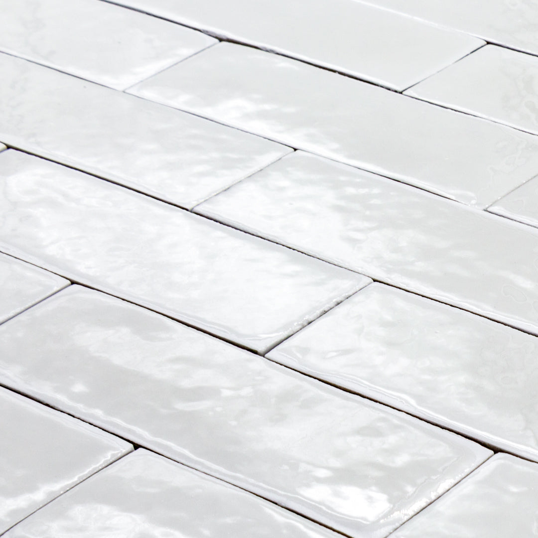 angled view of a group of popcorn cloud white 2x6 glossy subway tiles with a soft texture and uneven edges in a brick layout. 