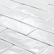 angled view of a group of popcorn cloud white 2x6 glossy subway tiles with a soft texture and uneven edges in a brick layout. 